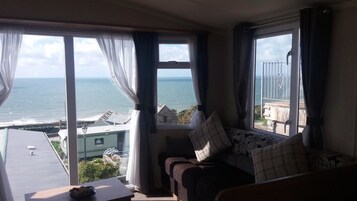 Una habitación con vista al mar, un sofá con cojines y una mesa con un bol.