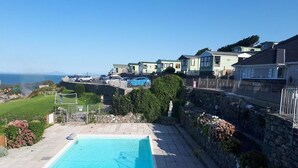 Ein Schwimmbecken mit einer Steinmauer und Blick aufs Meer.