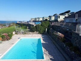 Una piscina con pared de piedra y vista al mar.