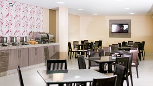 A modern dining area with a kitchen counter, buffet, and multiple tables and chairs. - Hotel São Lázaro (Brumado)