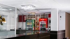 A modern hotel lobby with a glass partition, a Coca-Cola refrigerator, and a minibar. - Hotel São Lázaro (Brumado)