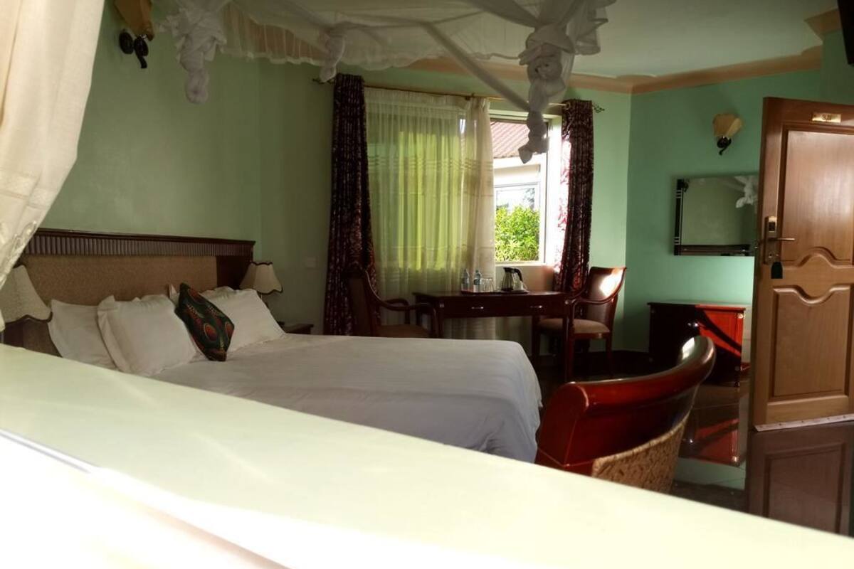 Quarto de hotel com duas camas, uma escrivaninha, uma cadeira e um guarda-roupa.