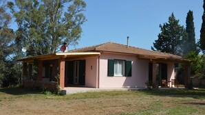 A single-story house with a tiled roof, a covered porch, and a small garden area. - Cozy vacation home on a farm, Bagno di Gavorrano, Tuscany (Bagno di Gavorrano)