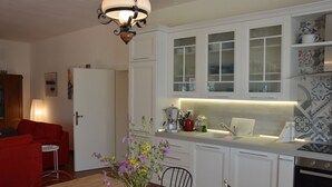 A modern kitchen with white cabinets, a built-in oven, and a dining area with a wooden table and chairs. - Cozy vacation home on a farm, Bagno di Gavorrano, Tuscany (Bagno di Gavorrano)