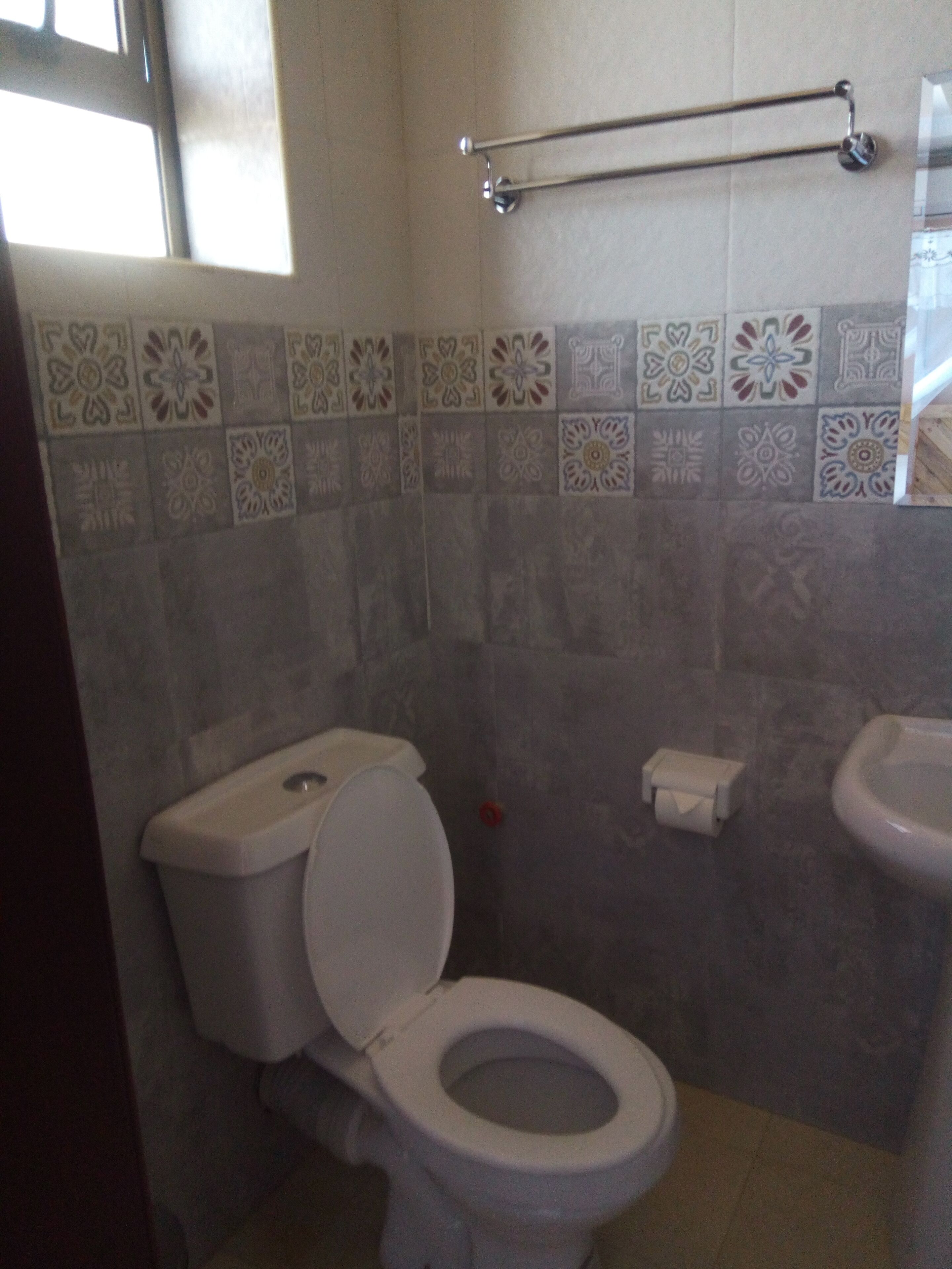 Egy fürdőszoba, amelyben WC, mosdókagyló és törölközőtartó található.