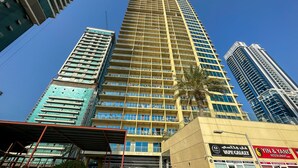 A high-rise building with multiple floors, large windows, and a yellow facade. - HiGuests - Lake view (Dubai)