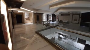 A spacious, modern interior with a marble floor, a glass railing, and a staircase leading to an upper level. - Hotel 18 Keys (Bhopal)