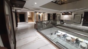A modern hotel lobby with a marble floor, glass railing, and a staircase leading to an upper level. - Hotel 18 Keys (Bhopal)