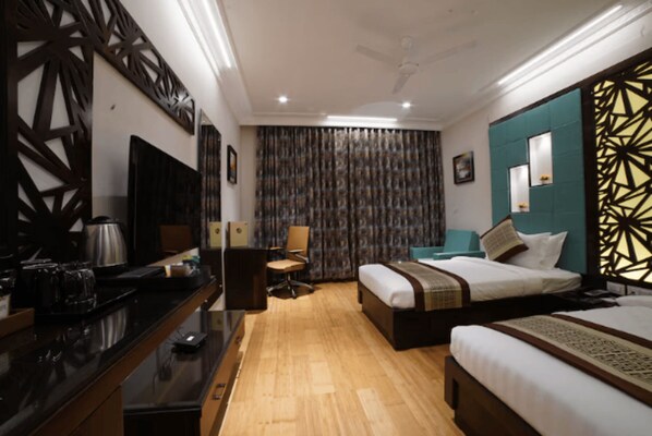 A modern hotel room with a wooden floor, a bed with a headboard, a desk with a chair, a television, and a decorative wall panel.