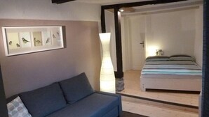 Ein Zimmer mit einer Couch, einem Bett und einem gerahmten Bild von Vögeln an der Wand.