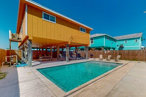 A residential backyard with a swimming pool, a covered patio area, and a wooden fence. - Private Pool, Pet Friendly, Golf Cart Access, Close to Beach (Port Aransas)