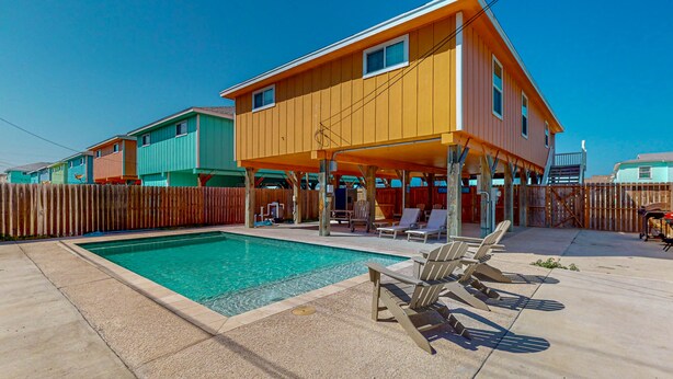 A two-story house with a swimming pool, outdoor seating, and a wooden fence. - Private Pool, Pet Friendly, Golf Cart Access, Close to Beach (Port Aransas)