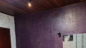 Un jacuzzi circular con piso de baldosas, techo de madera y pared texturizada color púrpura.