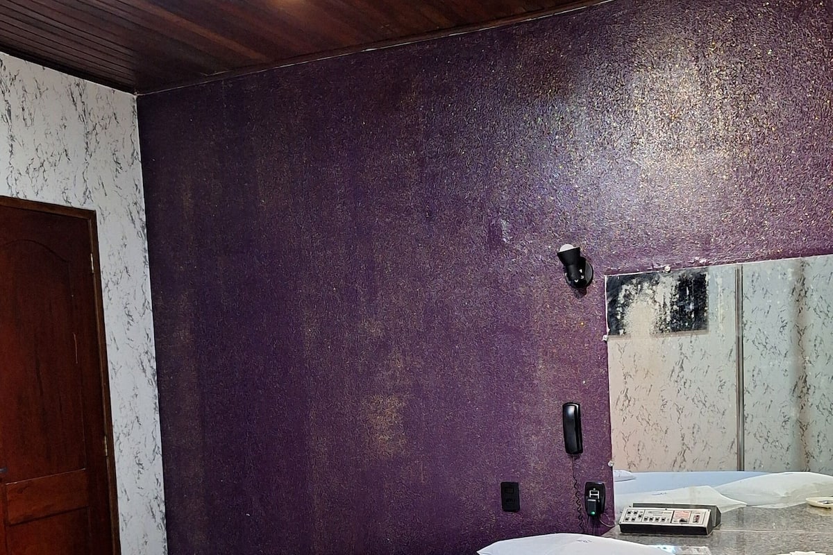 A circular jacuzzi with a tiled floor, a wooden ceiling, and a purple textured wall.