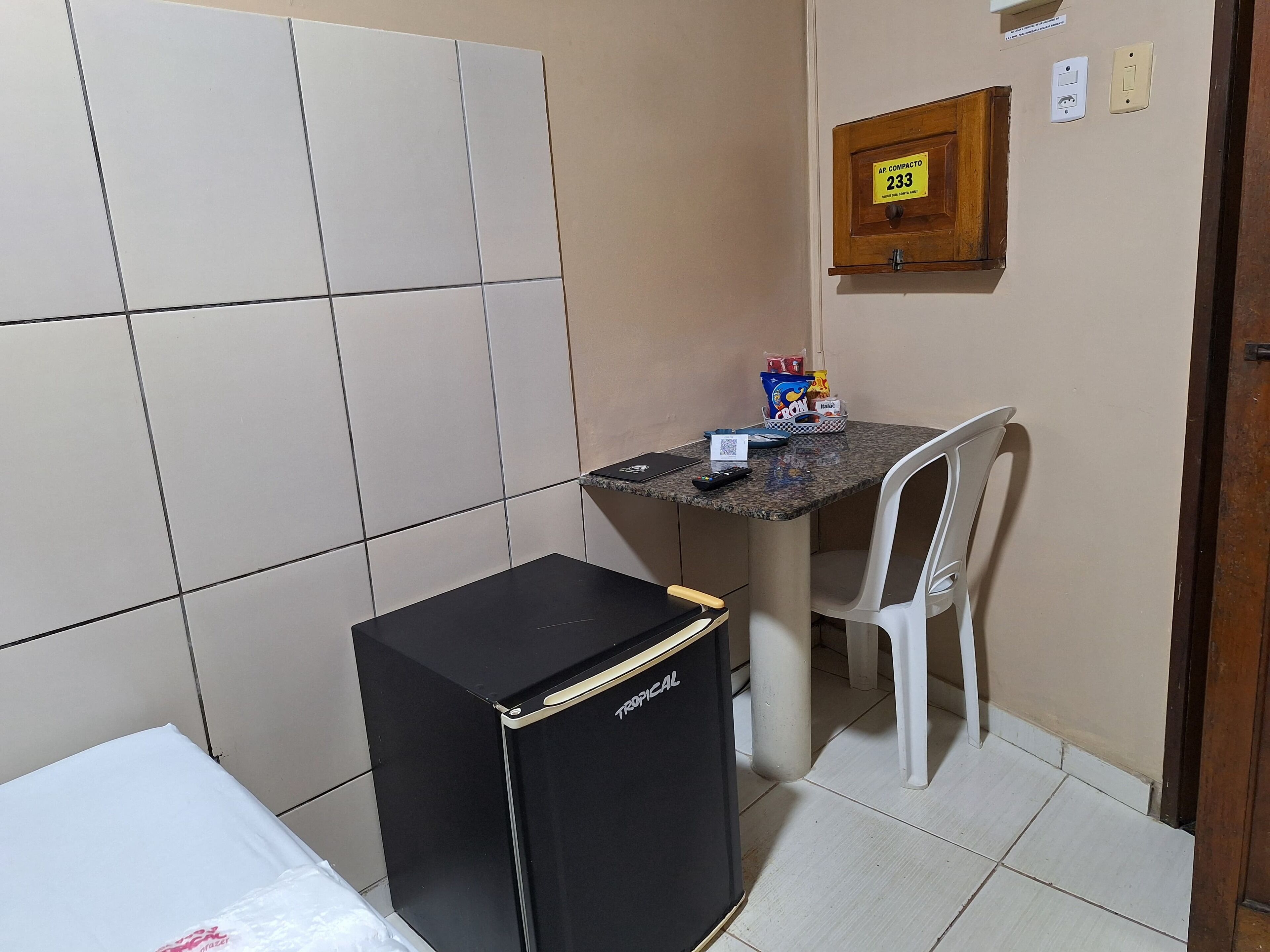 Una kitchenette compacta con refrigerador, una mesita y una silla.