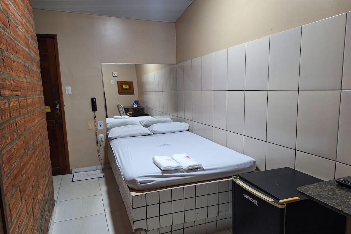 A hotel room with a bed, a small desk, and a tiled wall.
