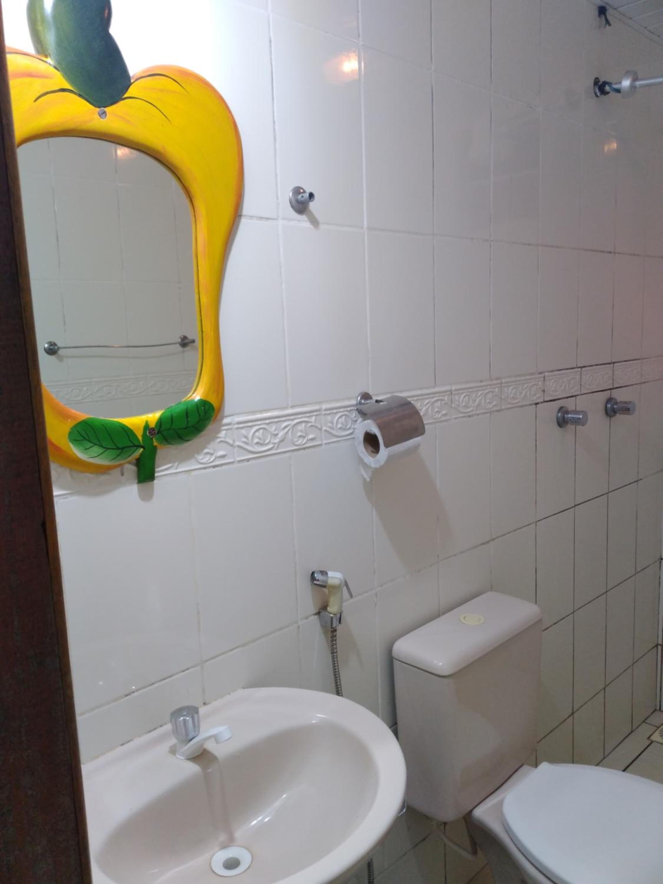 Un baño con un lavamanos blanco, inodoro y espejo con marco amarillo.