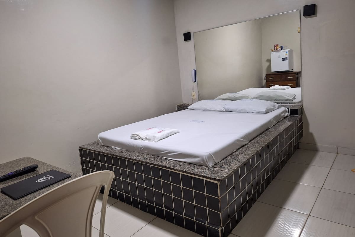A hotel room with a bed, a chair, a desk, and a mirror.