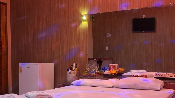 Habitación de hotel con una cama grande, un minibar, un refrigerador pequeño y una pared de madera.