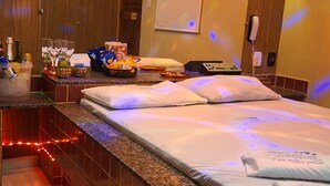 Una habitación de hotel con cama, minibar, baño y espejo.