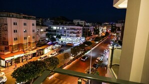 A nighttime view of a city street with buildings, cars, and pedestrians. - Papillonada Hotel (Kusadasi)