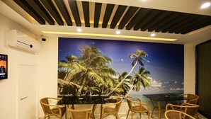 A room with a tropical mural, a glass table, wicker chairs, and a modern ceiling design. - Papillonada Hotel (Kusadasi)
