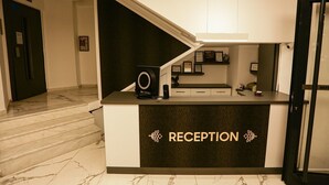 A reception desk with a marble floor, framed certificates on the wall, and a staircase leading to another area. - Papillonada Hotel (Kusadasi)