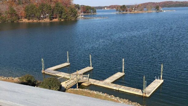 A lakeside view with a dock extending into the water, surrounded by trees and a clear sky. - Fall is a great time for a relaxing getaway at Birds Eye View, Bernard's Landing (Moneta)