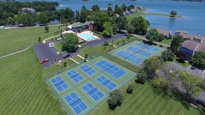 An aerial view of a sports complex with multiple tennis courts, a swimming pool, and a parking area. - Fall is a great time for a relaxing getaway at Birds Eye View, Bernard's Landing (Moneta)