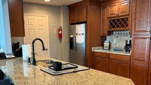 A kitchen with granite countertops, wooden cabinets, a stainless steel refrigerator, and a black faucet. - Fall is a great time for a relaxing getaway at Birds Eye View, Bernard's Landing (Moneta)
