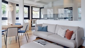 Un salon moderne avec un canapé, des fauteuils, une table à manger et une grande fenêtre.