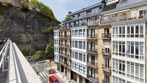 Un immeuble à plusieurs étages doté de balcons, de grandes fenêtres et d’un mur de pierre en arrière-plan.