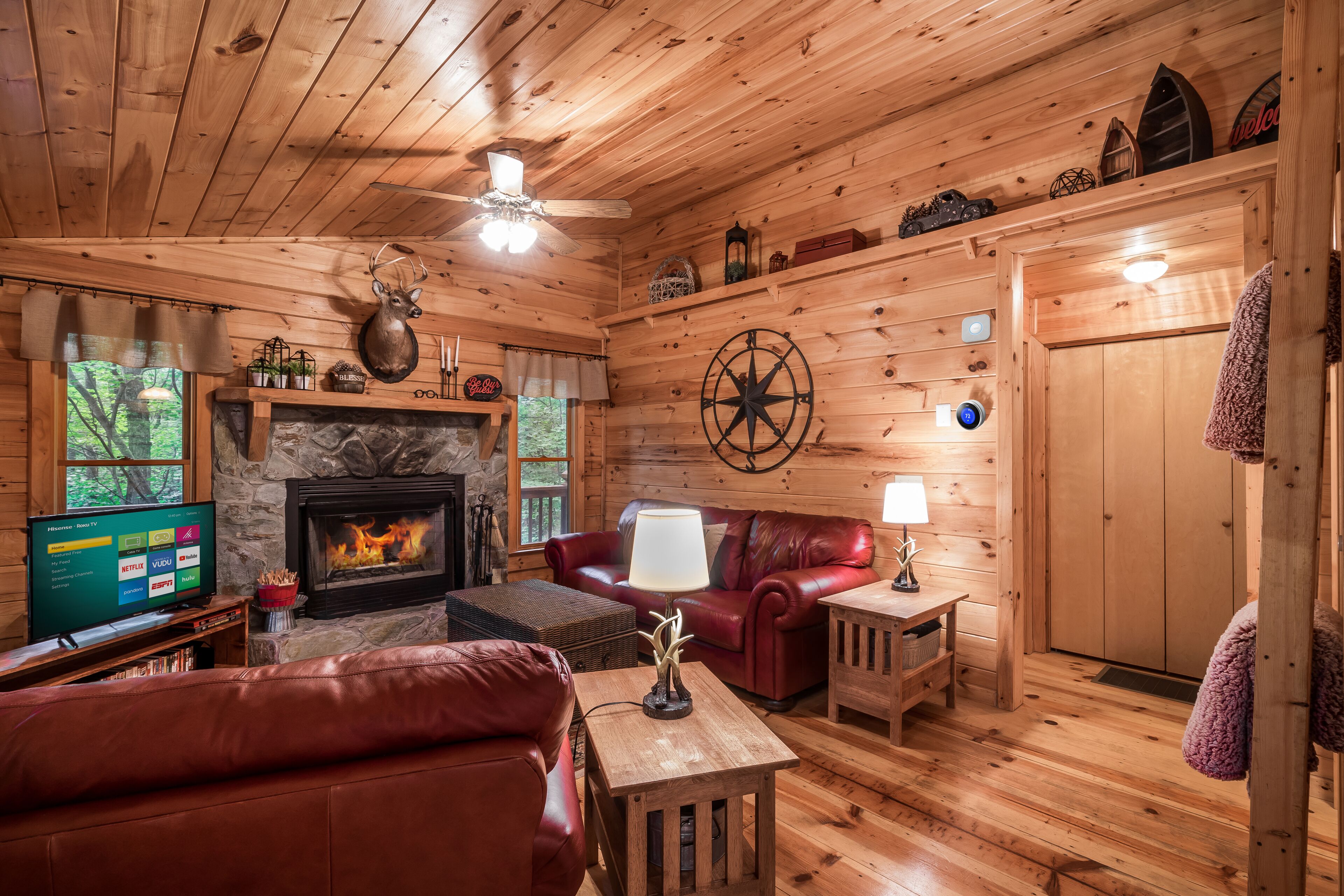 A cozy cabin interior with a stone fireplace, leather furniture, and wooden walls.