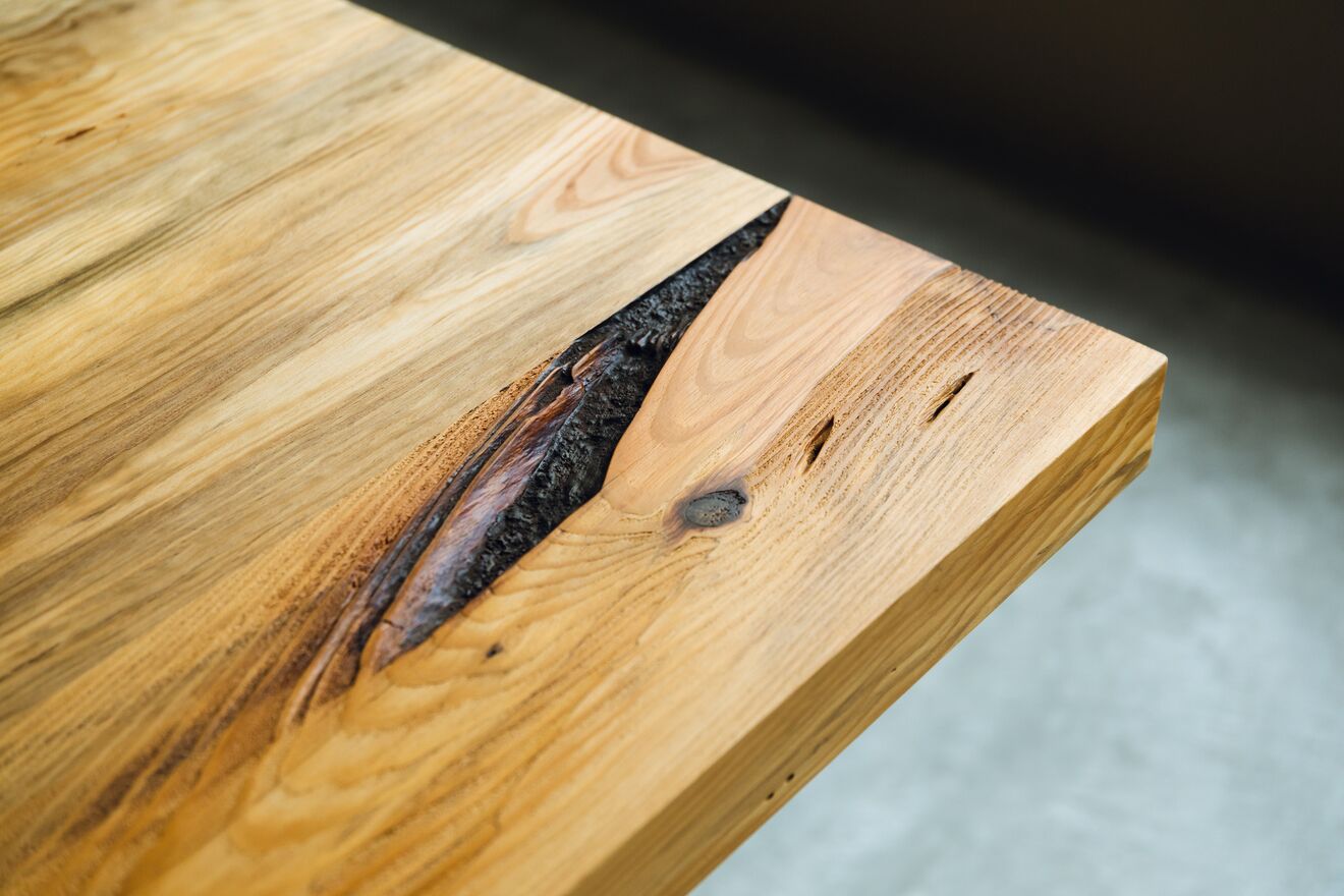 A close-up of a wooden table with a natural grain pattern and a dark stain accentuating the wood's texture.