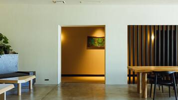 A modern interior with a wooden dining table and chairs, a bench, a potted plant, and a colorful abstract painting on the wall.