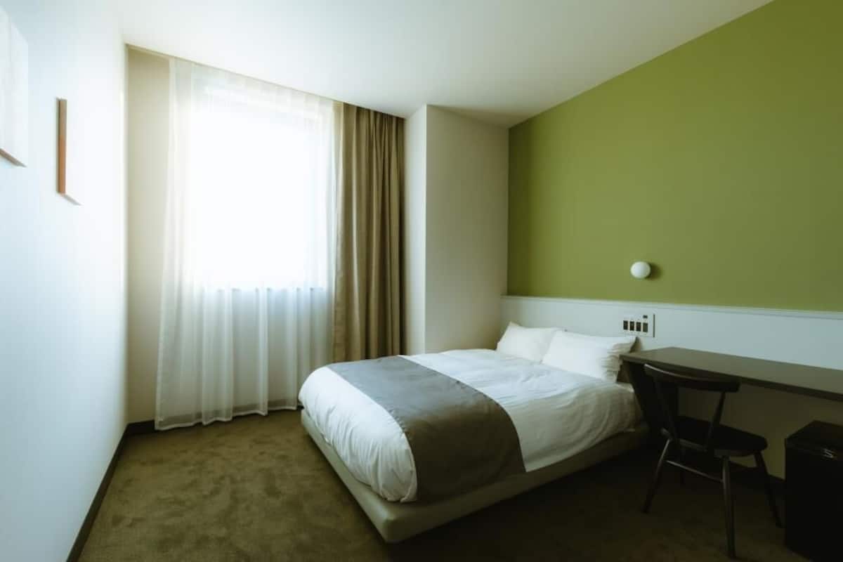 Una habitación de hotel con una cama, un escritorio y una silla.