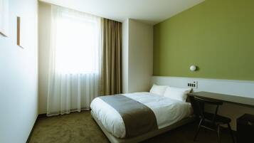Una habitación de hotel con una cama, un escritorio y una silla.