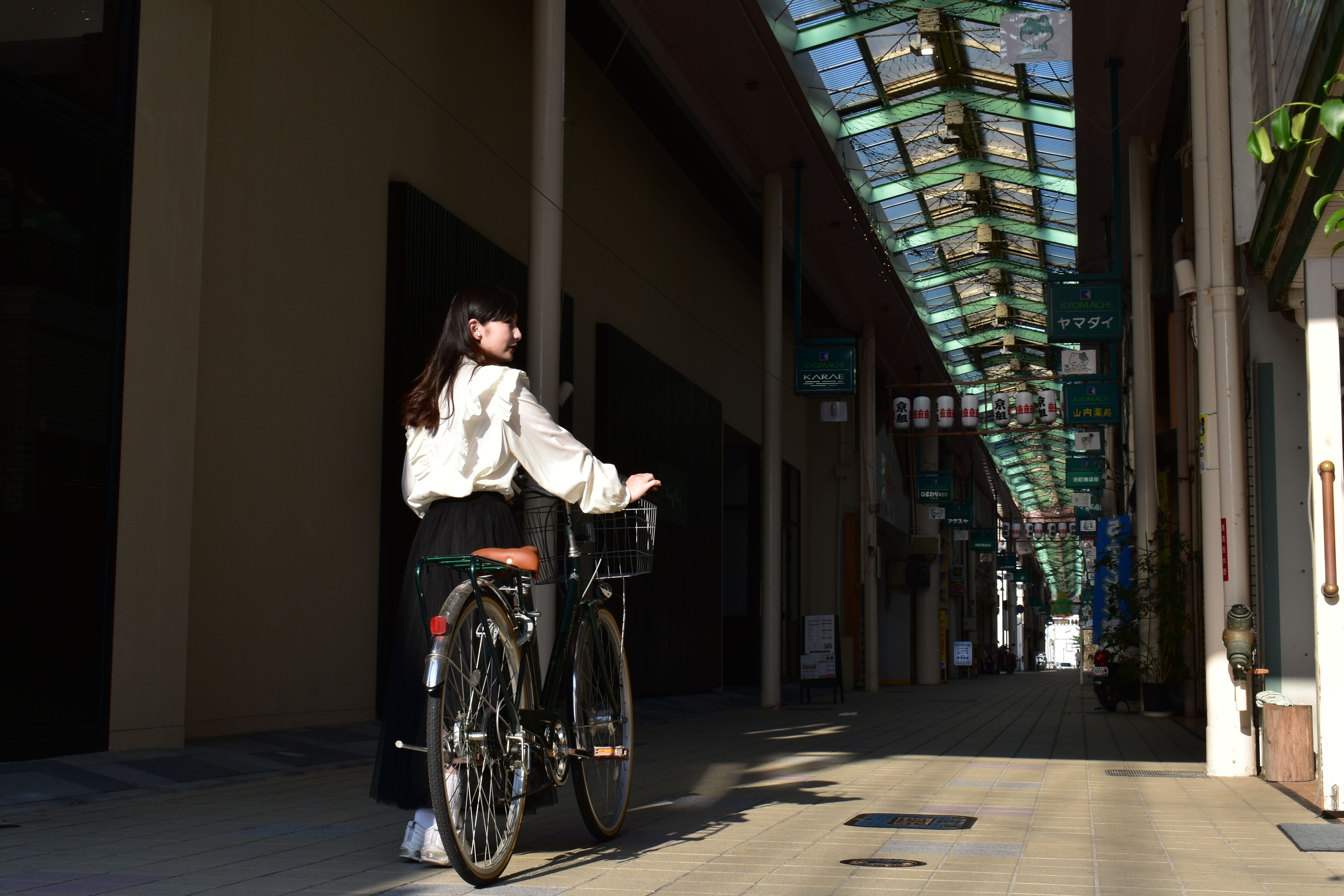 A corridor with a bicycle, a person, and signage.