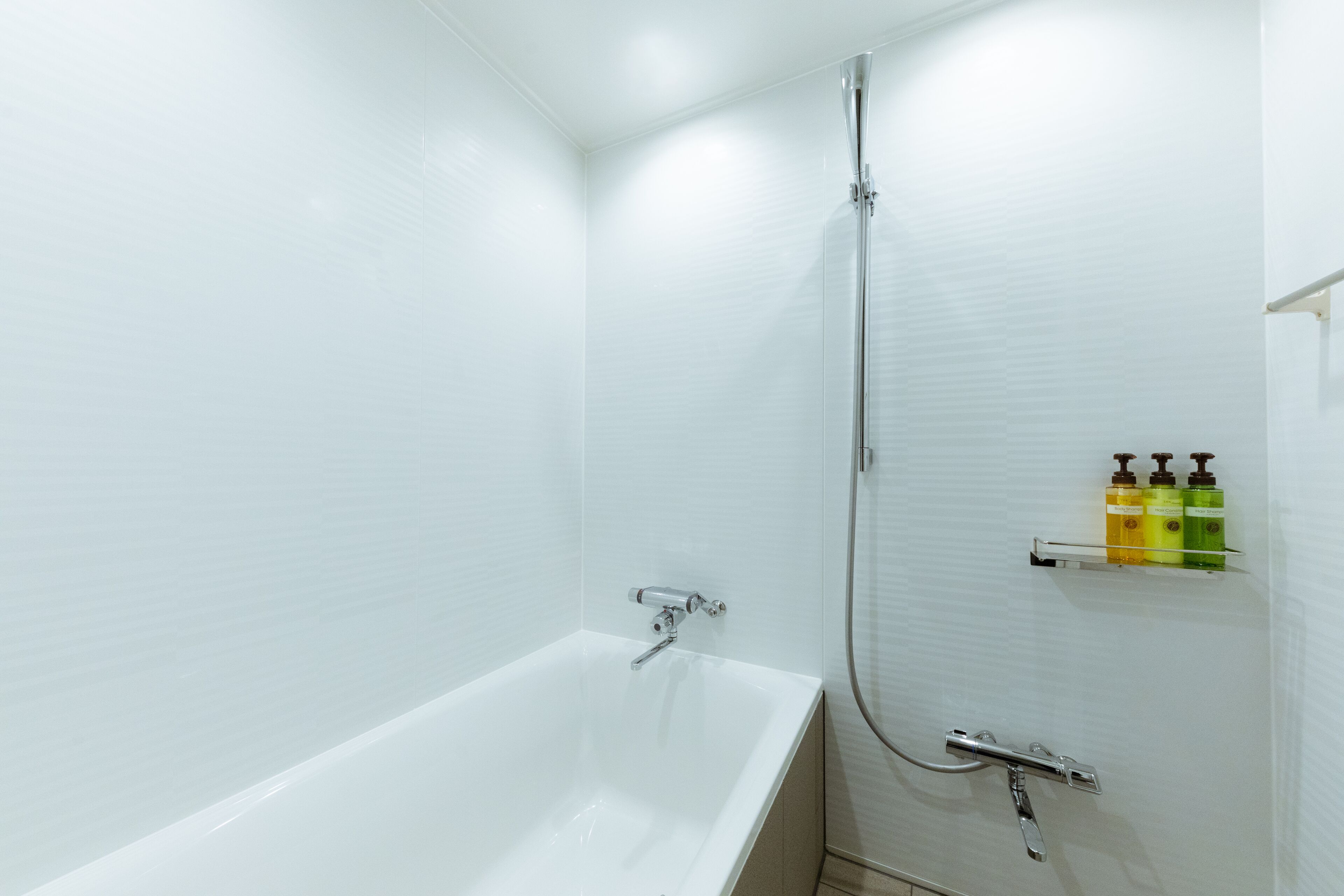 Une salle de bain moderne avec une baignoire blanche, une douche et une étagère contenant des articles de toilette.