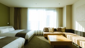 A hotel room with two beds, a sofa, a wooden coffee table, and a large window with sheer curtains. - Hotel Karae - Hostel (Karatsu)