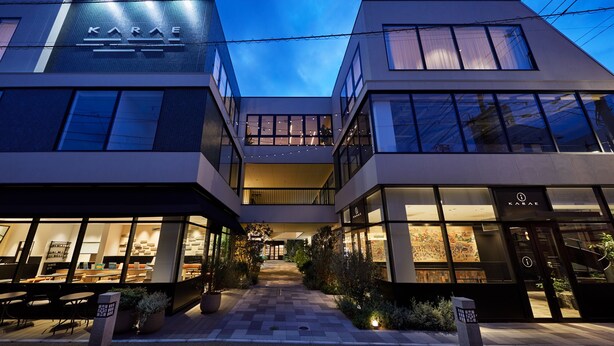 A modern building with a glass facade, a visible entrance, and outdoor seating areas. - Hotel Karae - Hostel (Karatsu)
