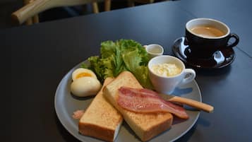 Un plato con tostadas, huevos, tocino, lechuga y una taza de café sobre una mesa.