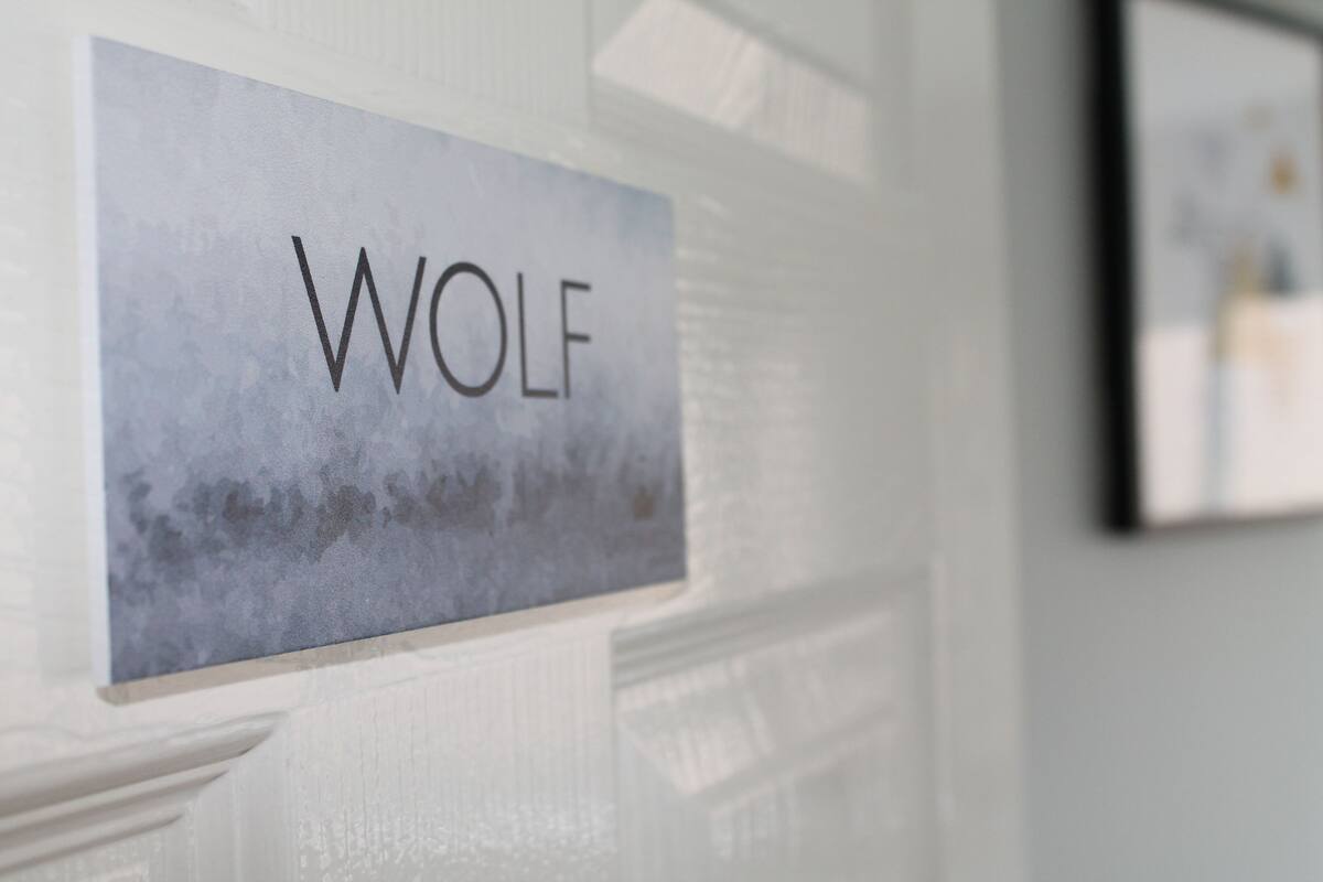 Una señal con la palabra 'WOLF' en una pared con textura.