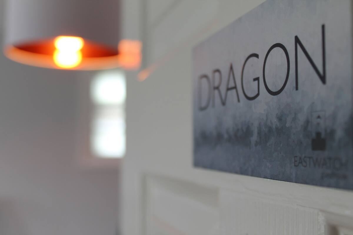 Un letrero con la palabra 'DRAGON' y una vista parcial de una habitación con una puerta blanca.