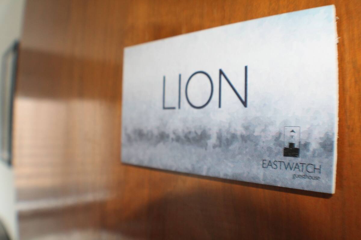 Un letrero con la palabra 'LION' y 'EASTWATCH guesthouse'.