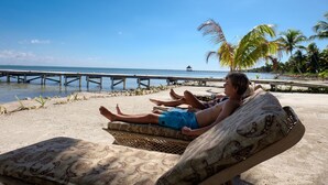A beach scene with a person relaxing on a patterned lounge chair. - 506 - 3rd Floor Ocean View Suite (San Pedro)