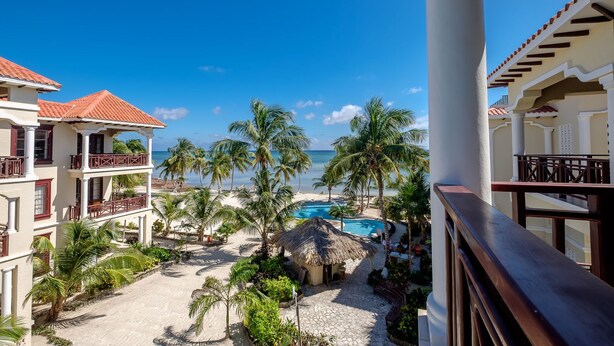 A resort with a pool, palm trees, and a view of the ocean. - 506 - 3rd Floor Ocean View Suite (San Pedro)