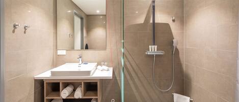 Un baño moderno con cabina de ducha de vidrio, un lavamanos con espejo y un perchero para toallas.