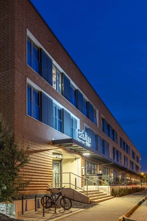 A modern hotel with a brick facade, large windows, and a well-lit entrance. - Park Inn By Radisson Wismar (Wismar)