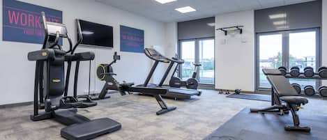 A gym with treadmills, weight machines, and dumbbells.